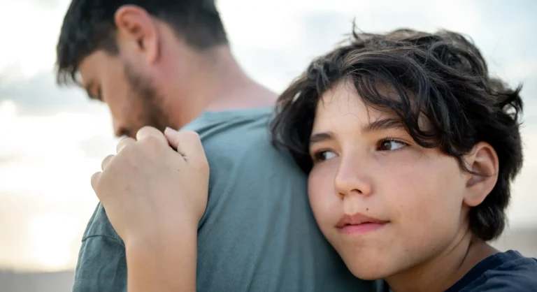 teenage boy snuggles with tenderness to the strong shoulder of the father