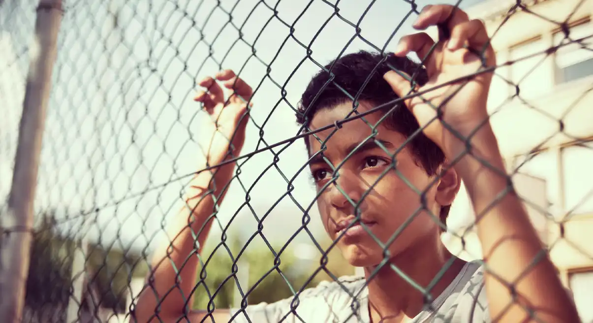 youth behind a fence barricade